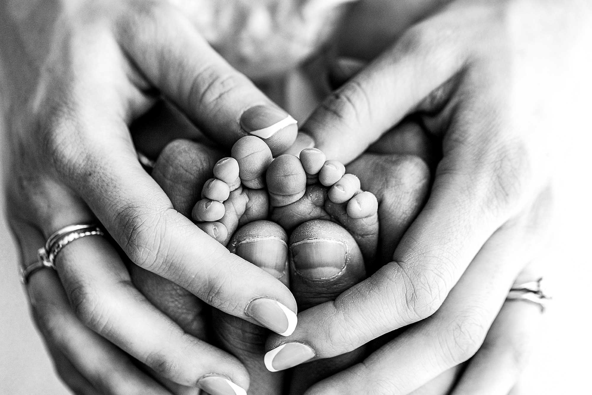 Macro Photography of parents hands and baby feet