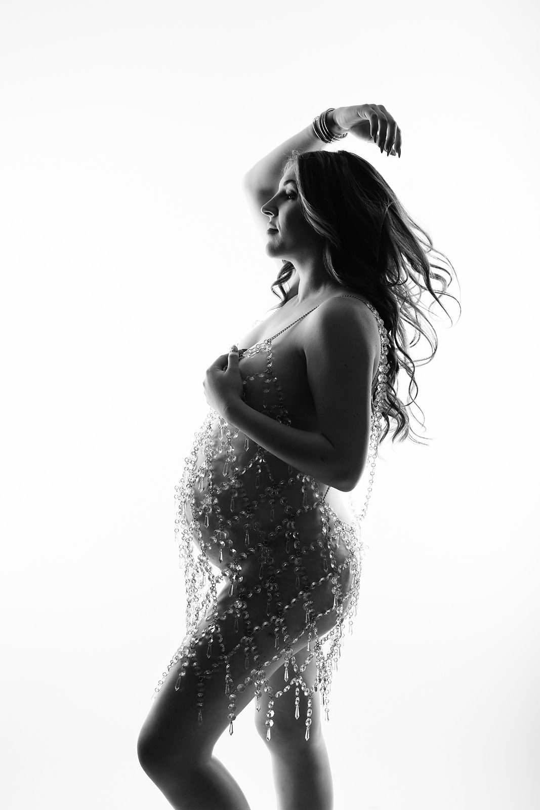 Minimalist studio maternity photography featuring an expected mother against a clean backlight backdrop