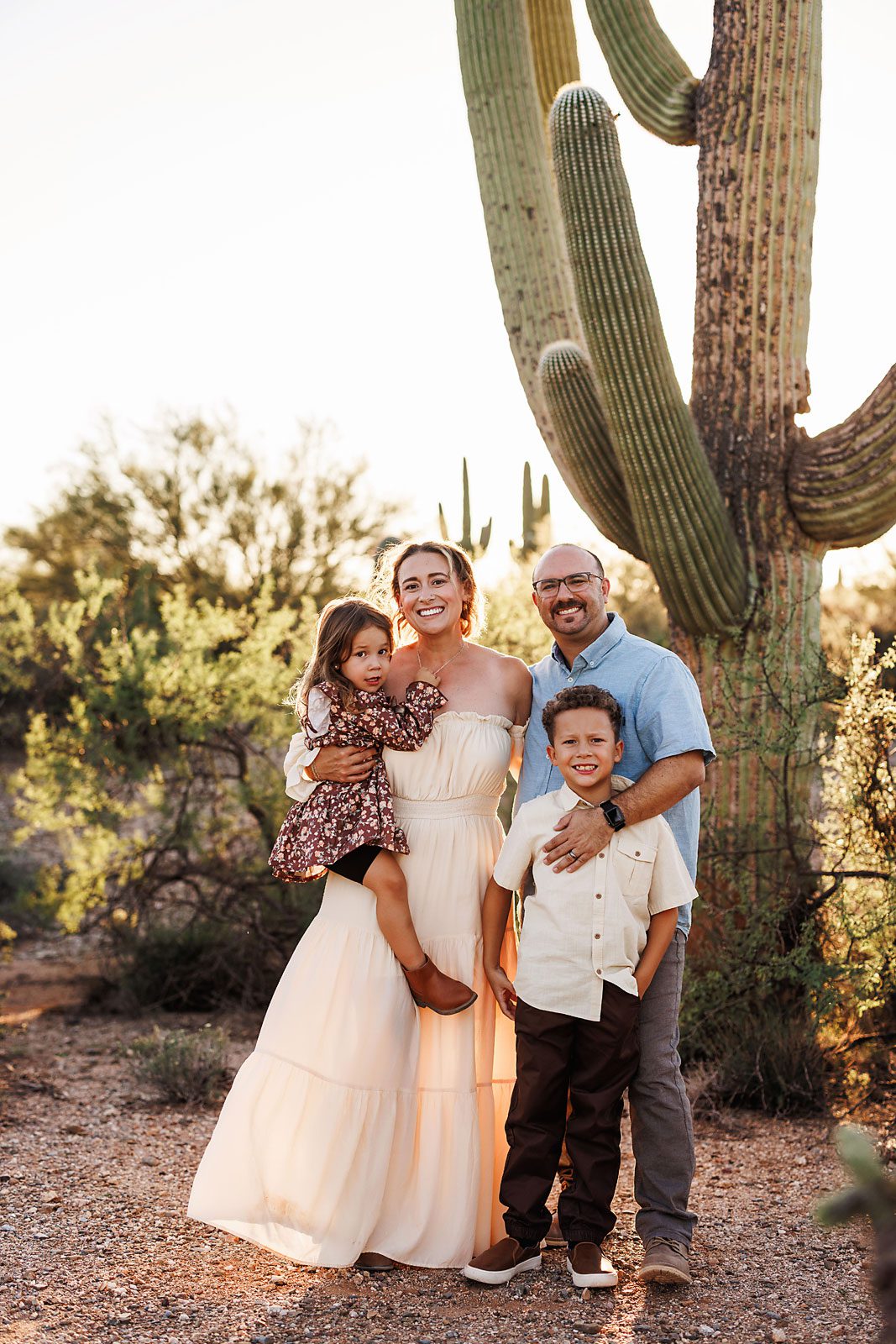 family portrait photographed outdoors at sunset with soft golden light and a natural desert landscape